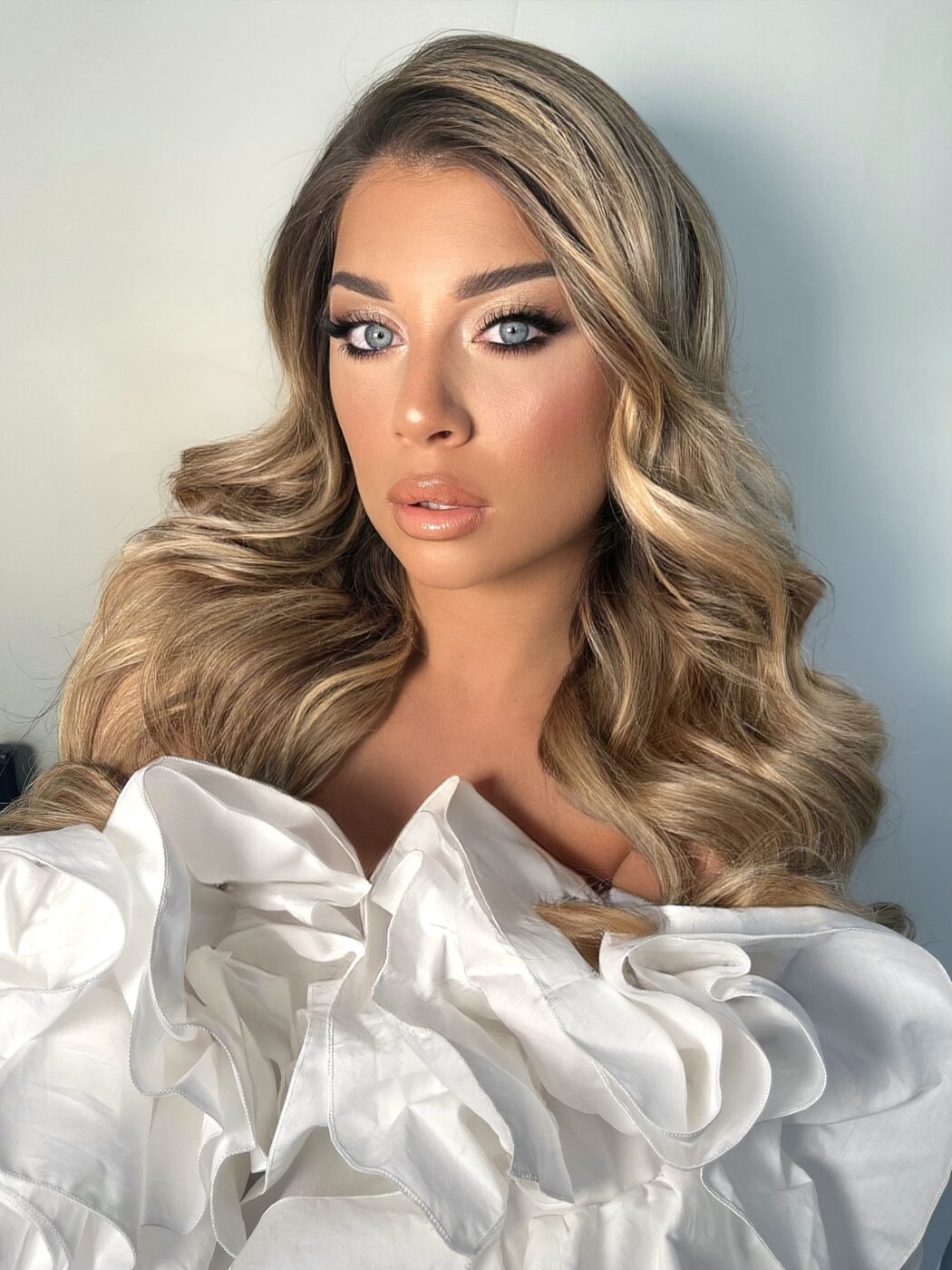 Maquillage glam smoky doré et brushing wavy blond chemise blanche à volants Cannes